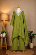 An olive green two-piece tunic and trouset set displayed on a mannequin in a styled indoor setting. The tunic features a draped, asymmetrical hem and a V-neckline with light blue and white embroidered detailing.